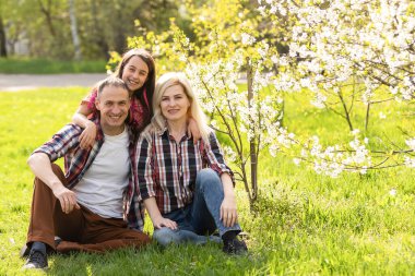 Mutlu genç aile dışarıda yeşil doğada birlikte vakit geçiriyor.
