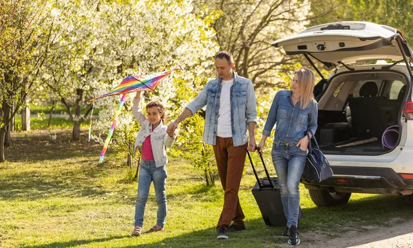 Ebeveynler ve çocuklar arabayla mola vermek için durdular. Mutlu aile arabayla seyahat eder. Araba yolculuğu konsepti. sağlıklı aile
