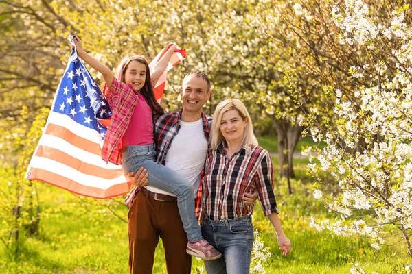 Gün batımında Amerika bayrağıyla mutlu bir aile.