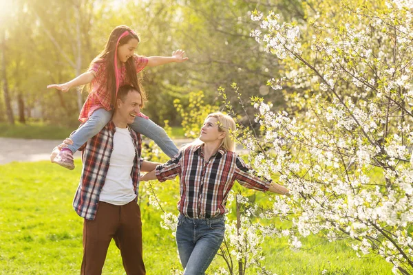 Boldog fiatal család a lánnyal, aki együtt játszik a virágfarmon. — Stock Fotó