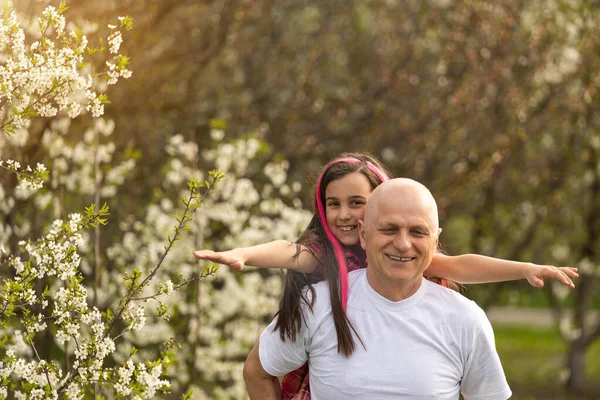 Happy granddaughter hugging her smiling grandfather on green lawn — Stockfoto