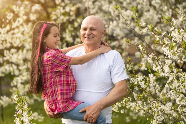Glückliche Enkelin umarmt ihren lächelnden Opa auf grünem Rasen — Stockfoto