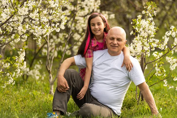 Happy granddaughter hugging her smiling grandfather on green lawn — Stockfoto