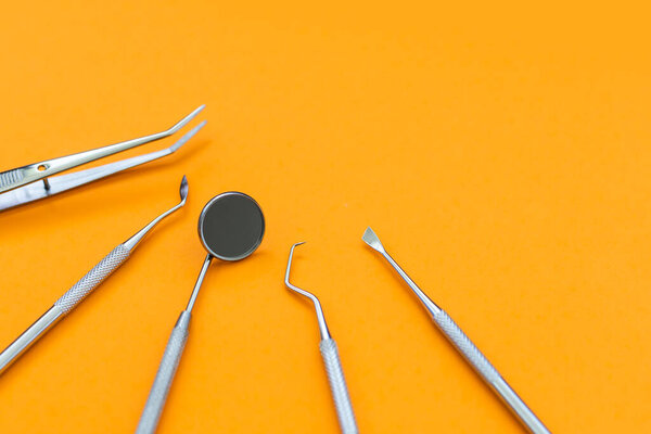 Dental mirror and other tools on orange background