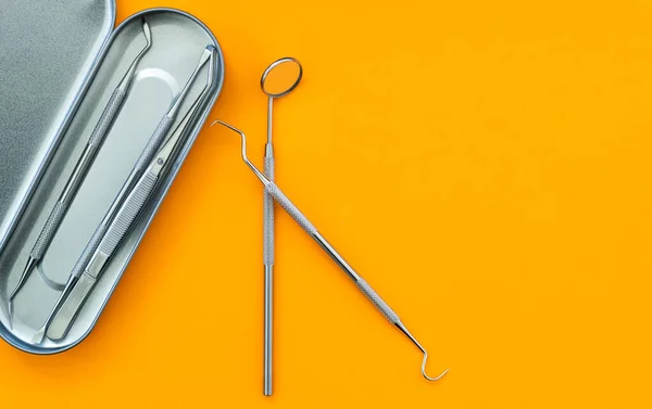 Dental mirror and other tools on orange background — Fotografia de Stock