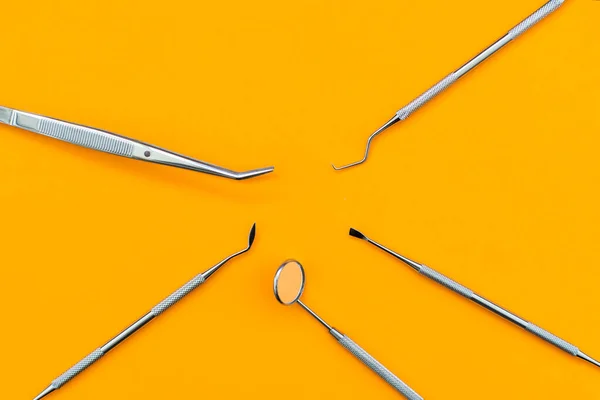 Espelho dental e outras ferramentas sobre fundo laranja — Fotografia de Stock