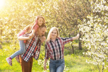 Mutlu bir aile baharda çiçek açan bir bahçede birlikte iyi vakit geçirir.