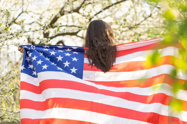 Glad söt liten flicka ler och viftar med amerikansk flagga. Patriotisk högtid. Glad unge, söt liten flicka med amerikansk flagga. USA firar den 4 juli. Begreppet självständighetsdag. — Stockfoto