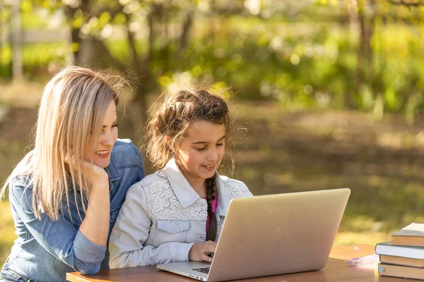 Η μητέρα βοηθάει την κορούλα της να χρησιμοποιήσει φορητό υπολογιστή. Παιδί σπουδάζει στο σπίτι κάνει τα μαθήματά της ή έχει online μάθημα. Έννοια της κατ 'οίκον εκπαίδευσης. — Φωτογραφία Αρχείου