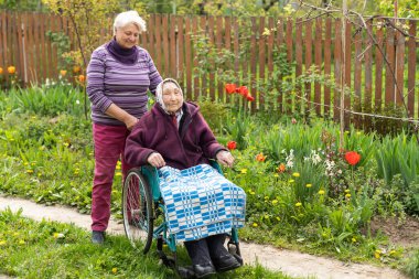 Senior care assistant with very old disabled woman in nursing home.
