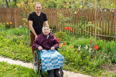 Senior care assistant with very old disabled woman in nursing home.
