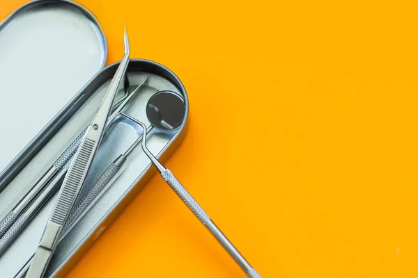 Dental mirror and other tools on orange background — Fotografia de Stock