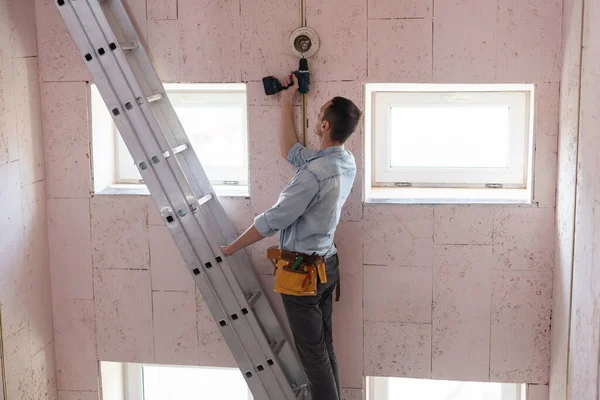Un electricista fijando cables, instalando luz en el techo — Foto de Stock