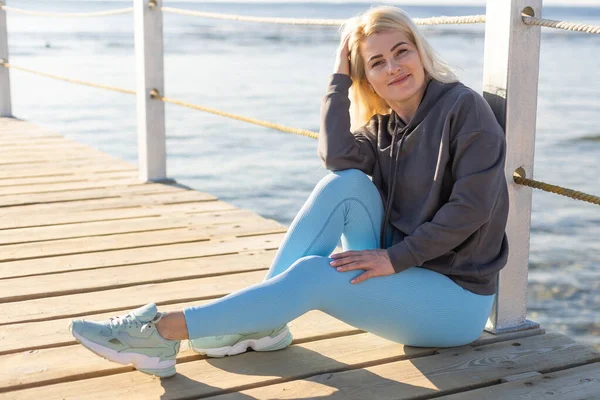 Genç bir kadın güneşli bir günde denizin önünde dubada