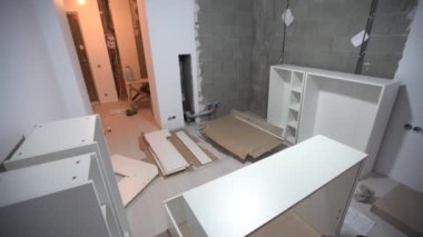 Tamamlanmamış mobilya parçaları, metal vidalar ve arkada mobilya montajı için kullanım kılavuzuyla yerde duran aletler. Yeni eve taşınıyorum..