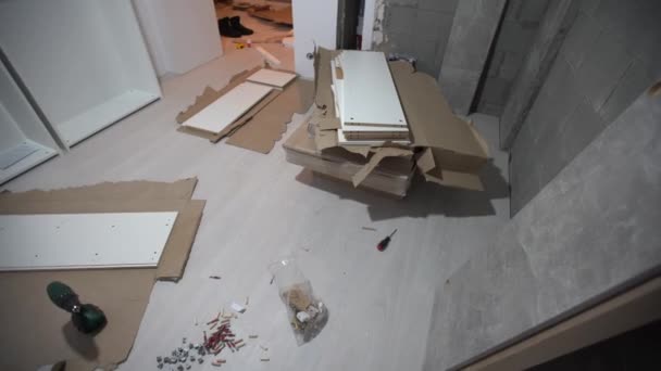 Opened box with furniture assembly parts and tools on the floor. Self assembling and DIY furniture at home concept. Bolts and screws — Stockvideo