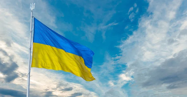 Ukrainian national flag disperses in the wind. Flag of Ukraine on the blue sky. Ukrainian banner or background. illustration — Zdjęcie stockowe
