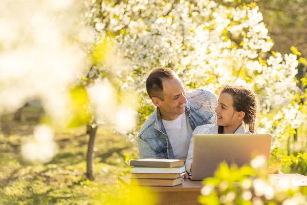 Mała dziewczynka z ojcem studiuje na laptopie odkryty — Zdjęcie stockowe