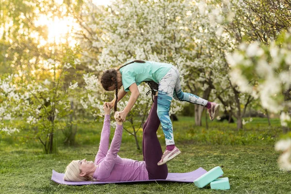 Anne ve kızı açık havada yoga, sağlıklı yaşam yapıyor.