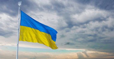 Ukrainian national flag disperses in the wind. Flag of Ukraine on the blue sky. Ukrainian banner or background. illustration
