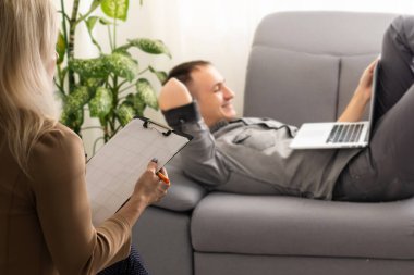 Kadın psikolog psikolog, psikoloji seansı sırasında oturan işadamı müvekkilini dinliyor.