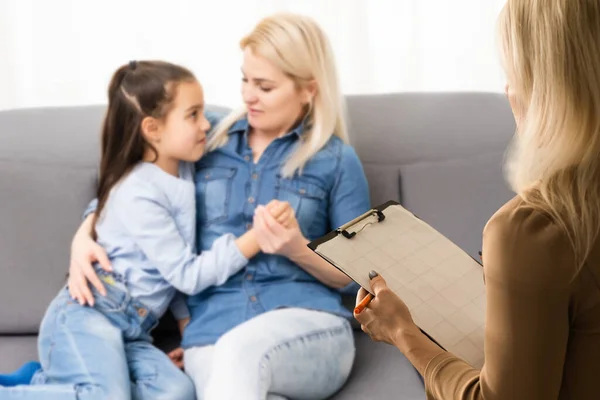 Rear view of female psychologist helping young family with a kid to solve child development problems. Family sitting on a sofa — Stock Photo, Image