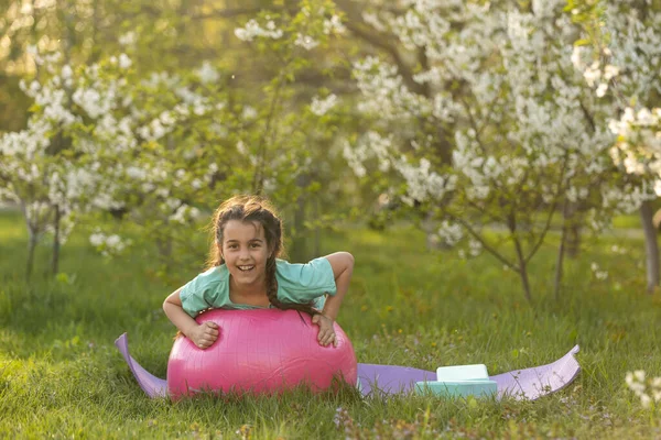 Děvčátko, které cvičí jógu, roztahuje se na trávě za slunečného letního dne. Flexibilní dítě, cvičící gymnastiku. Sport, učení, fitness, strečink, jóga, aktivní životní styl. — Stock fotografie