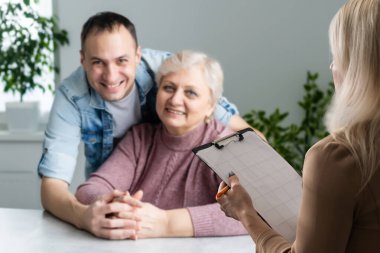 Aile danışmanıyla konuşuyorum. Çocuğuyla gülümseyen ebeveynler danışmanla tartışıyor. Çok ırklı aile bir finans danışmanıyla buluşuyor..