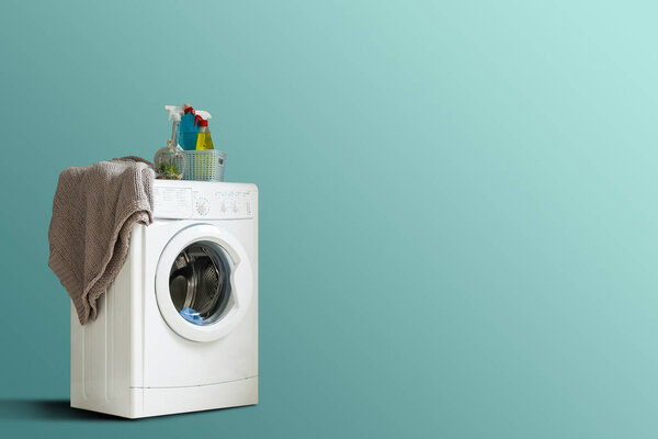 Clothes washing machine in laundry room interior on blue wall, copy space.