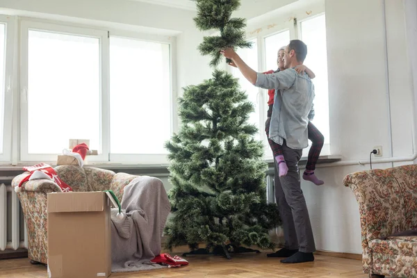 男と彼の小さな娘はクリスマスの花輪を飾ることを学ぶ。クリスマスの花輪を作る家族。お正月飾り — ストック写真