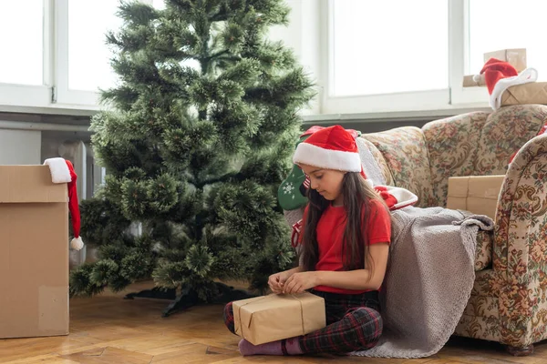 Feliz Natal e Boas Festas. Menina criança bonito alegre com presente. Kid segura uma caixa de presente perto da árvore de Natal dentro de casa. — Fotografia de Stock