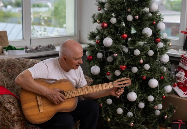 Conceito de família de pessoas felizes Velho homem sênior apreciando a guitarra no sofá da casa no Natal — Fotografia de Stock