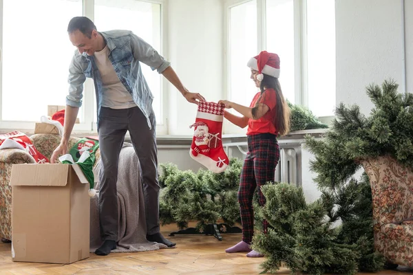 Vater und Tochter stellen Weihnachtsbaum zusammen, lächeln - Weihnachten, Urlaub, Winterkonzept, Familienaktivitäten. — Stockfoto