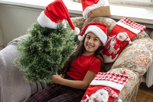 Зимние праздники и люди концепция - маленькая девочка делает искусственную елку — стоковое фото
