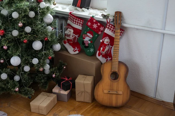 Guitar with decorated Christmas Tree in the background — Stock Photo, Image