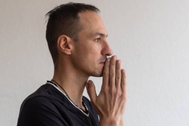 Fotoğrafçı, faiz ifadesini bir kenara bırakıp, elini dudaklarına yaklaştırıyor. Stüdyoda beyaz arka planda izole edilmiş güzel bir genç adam. Metin ve reklam için boş bir alanı var..