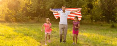 Gün batımında Amerika bayrağıyla mutlu bir aile..