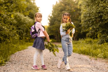 Sonbahar günü sırt çantalı mutlu okul çocukları, doğada kamp yaparken eğlenen heyecanlı çocuklar..