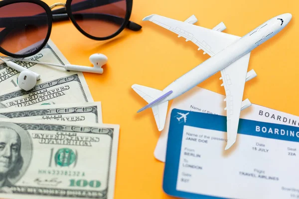 Travel concept, air ticket, money, headphones over yellow background.