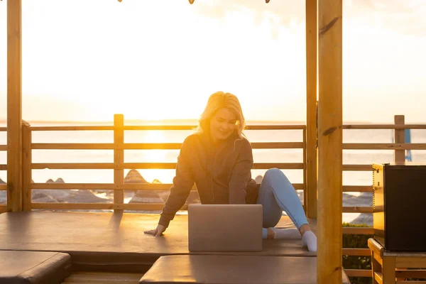 Vrouw Met Een Laptop Het Strand Tijdens Zonsondergang — Stockfoto