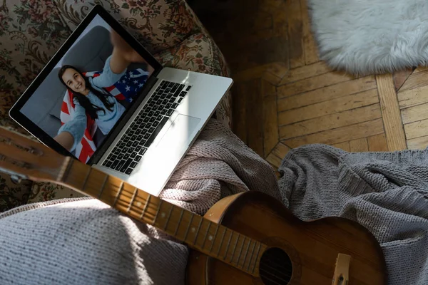小さな子供が家で練習しながらアコースティックギターを弾いてノートパソコンでオンラインコースを見て — ストック写真