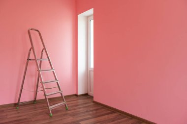 Kapalı alandaki boş duvara karşı katlanabilir krom merdiven..