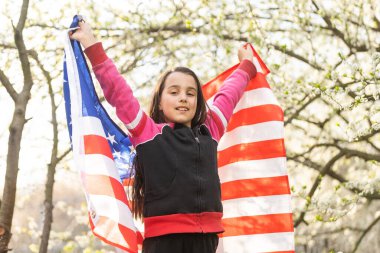 gülümseyen ve dışında Amerikan bayrağı sallayarak mutlu sevimli küçük kız. gülen çocuk 4 Temmuz - Bağımsızlık günü kutlamaları.