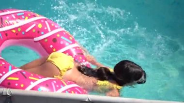 Kız şişme yüzük çalıyor. Bahçedeki havuzda..