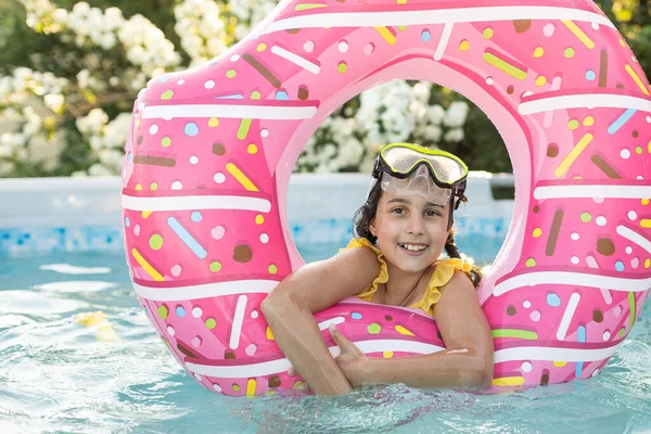 Adorable little girl with inflatable ring at swimming pool