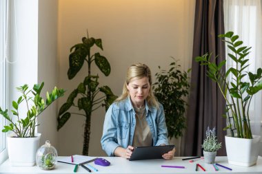 Ofisinde dijital tablet kullanan genç bir iş kadını.