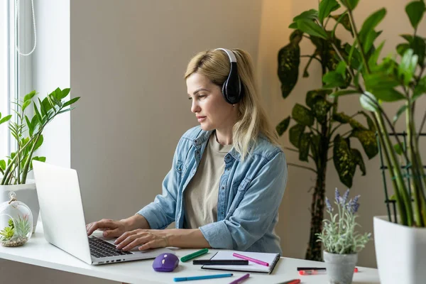 Laptop ekranına bakıp gülümseyen genç bir kadın, mesajda iyi haberler okuyor, video izliyor, sosyal ağda sohbet ediyor ya da evde online alışveriş yapıyor, bilgisayarla boş vakitlerin keyfini çıkarıyor.