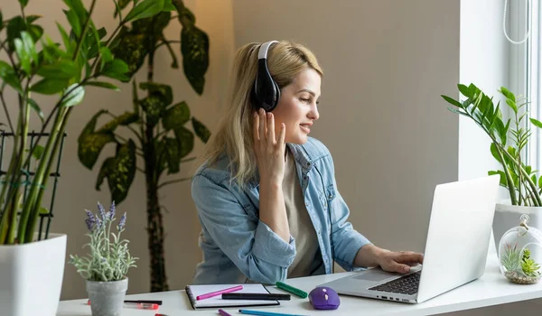 Bilgisayarda uzaktan kumandalı derslerde öğretmenlik yapan, öğrencileri dinleyen, okul sınıfında ödev yazan genç öğretmen.