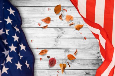Tahta masa üzerinde akçaağaç yaprakları olan küçük Amerikan bayrağı. Görünümün üstünde