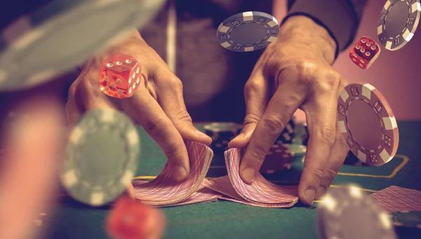 賭けのためのゲームテーブルを渡って色のポーカーチップの大規模なスタックを押すギャンブラーの男の手 — ストック写真